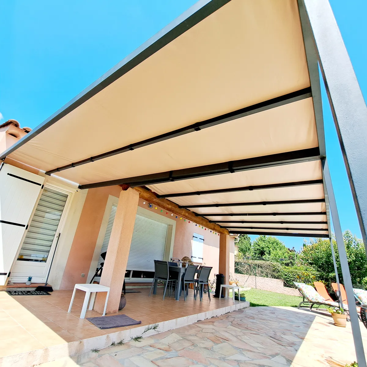 Pergola aluminium à toile rétractable au-dessus d'une terrasse repas ensoleillée