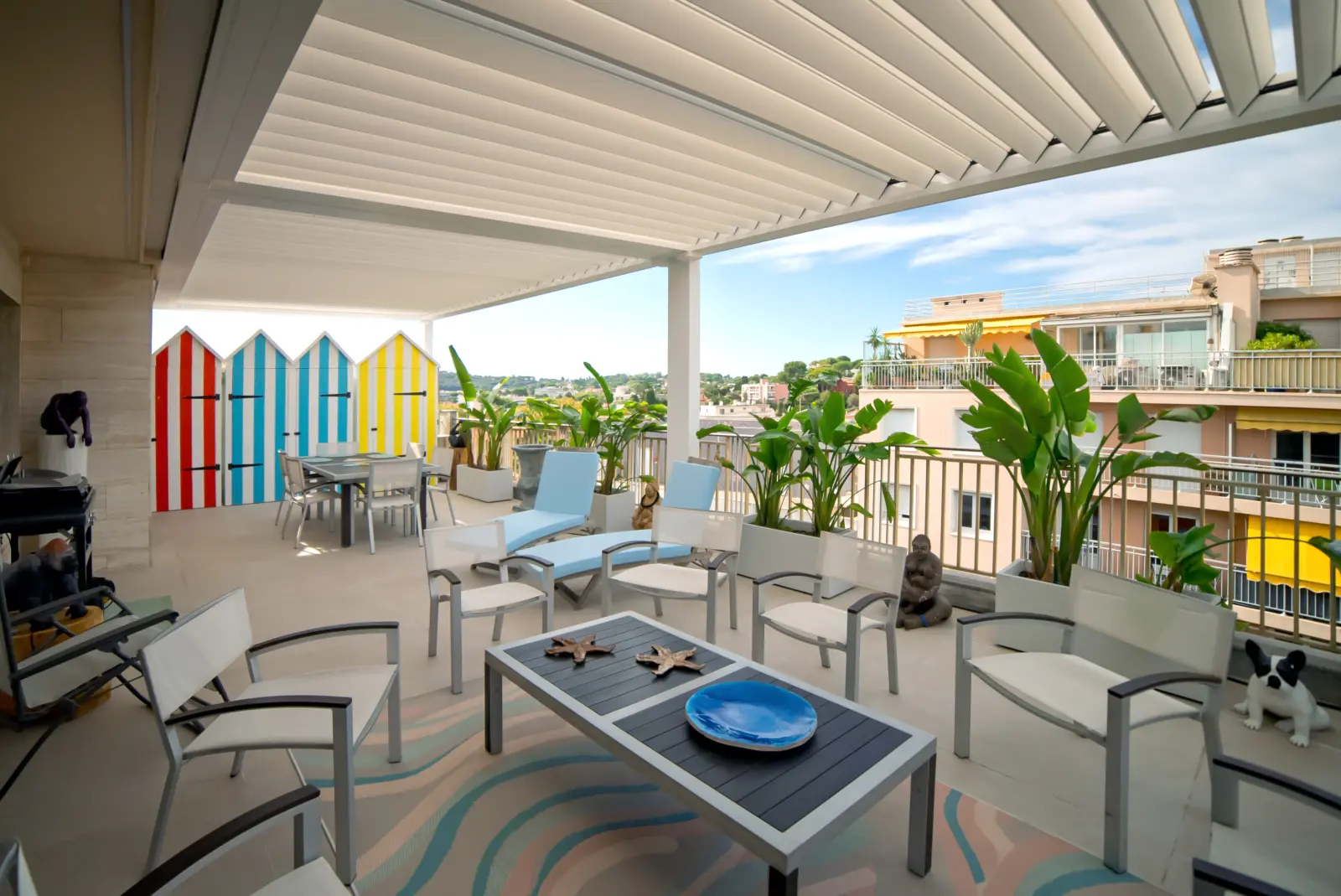 Pergola bioclimatique aluminium blanc au-dessus d'un salon extérieur sur terrasse