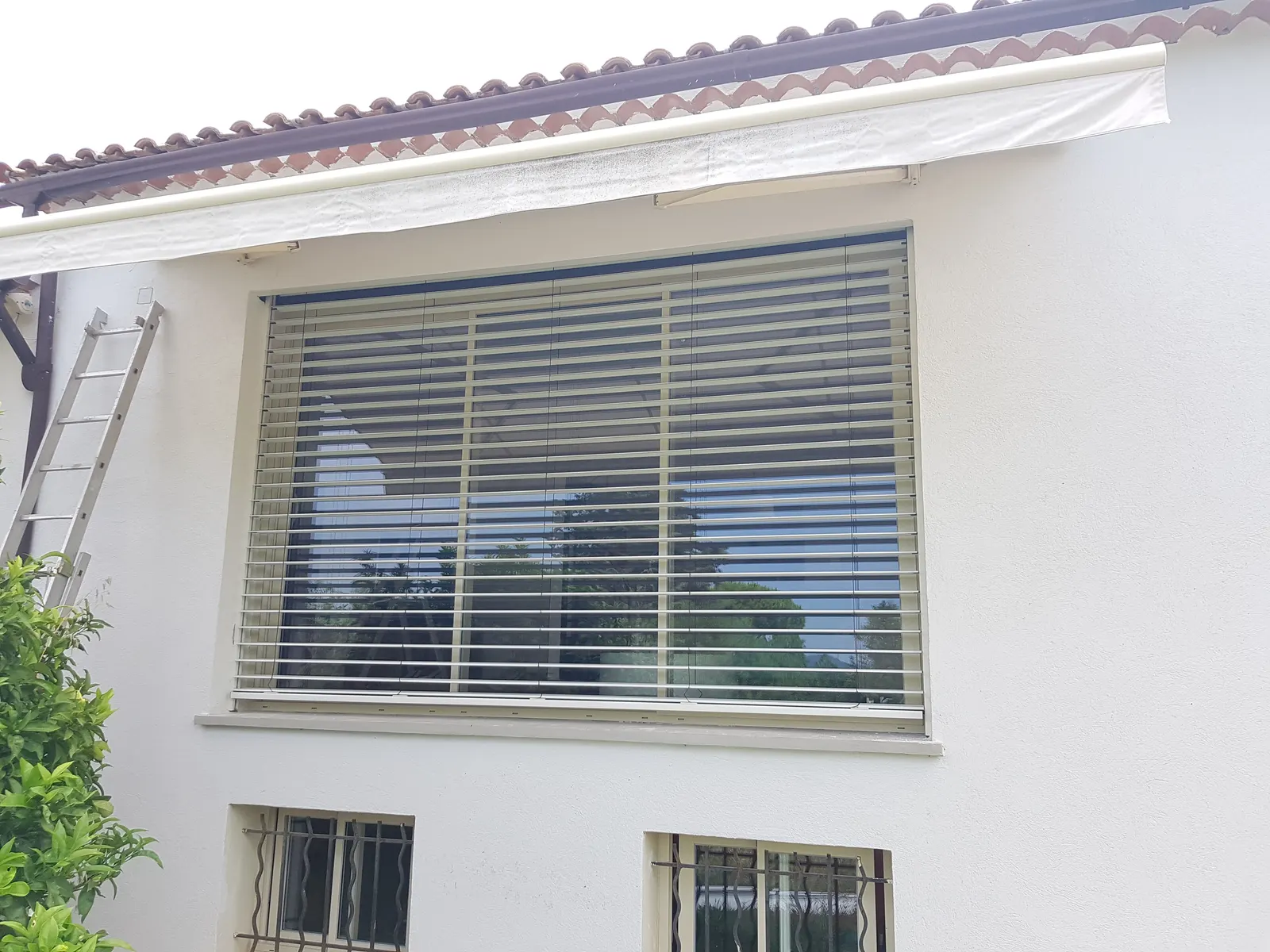 Brise-soleil orientable installé sur fenêtre avec vue sur jardin