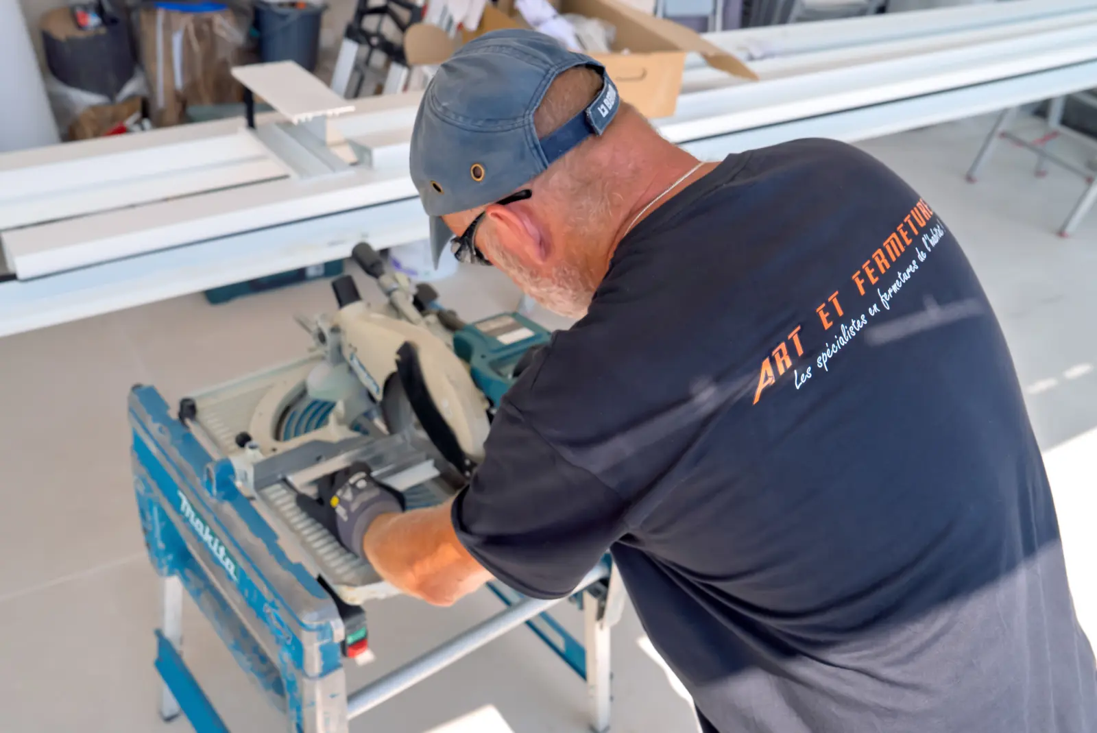 Poseur Art & Fermetures découpant un profilé aluminium sur chantier de pergola